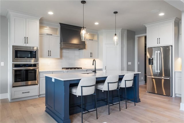 1113 Hummingbird Ct, Greenwood, MO 64034 - kitchen featuring stainless steel appliances, custom range hood, backsplash, light wood-type flooring, and light countertops