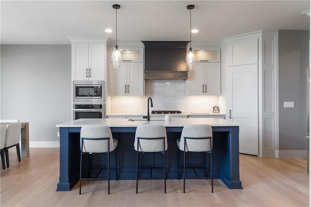 1113 Hummingbird Ct, Greenwood, MO 64034 - kitchen with stainless steel appliances, premium range hood, a kitchen island with sink, light countertops, and recessed lighting