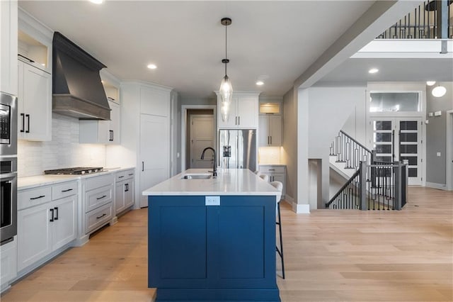 1113 Hummingbird Ct, Greenwood, MO 64034 - kitchen featuring appliances with stainless steel finishes, premium range hood, decorative backsplash, light wood-style flooring, and light countertops