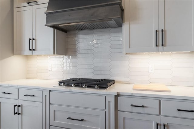1113 Hummingbird Ct, Greenwood, MO 64034 - kitchen with custom range hood, tasteful backsplash, and stainless steel gas cooktop