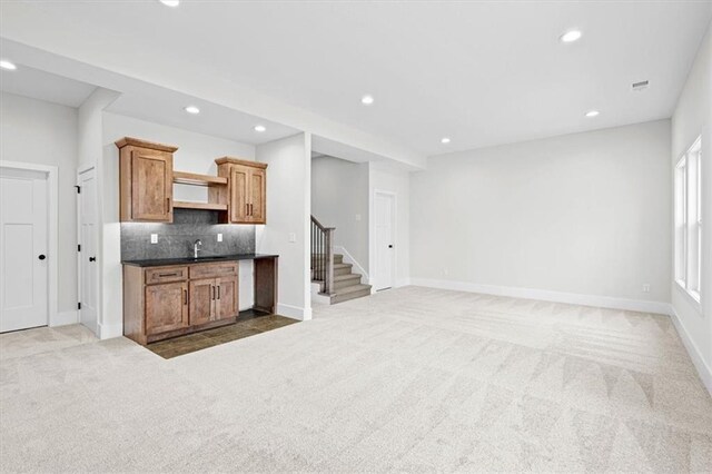 3932 SW Flinkrock Dr, Lees Summit, MO 64082 - kitchen with carpet floors, recessed lighting, backsplash, dark countertops, and brown cabinetry