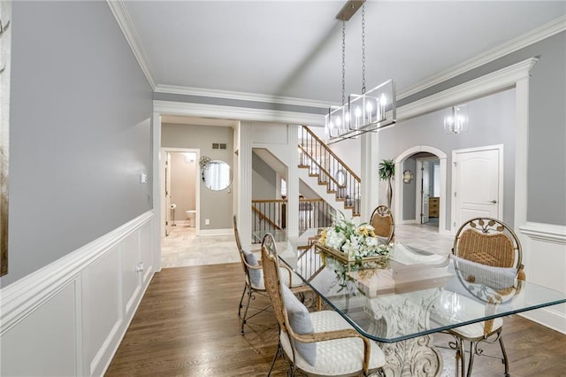 1021 SW Summit Falls Dr, Lees Summit, MO 64081 - dining room featuring arched walkways, crown molding, stairway, a decorative wall, and wainscoting