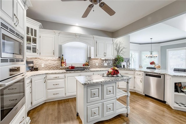 1021 SW Summit Falls Dr, Lees Summit, MO 64081 - kitchen with appliances with stainless steel finishes, decorative backsplash, a peninsula, a ceiling fan, and recessed lighting