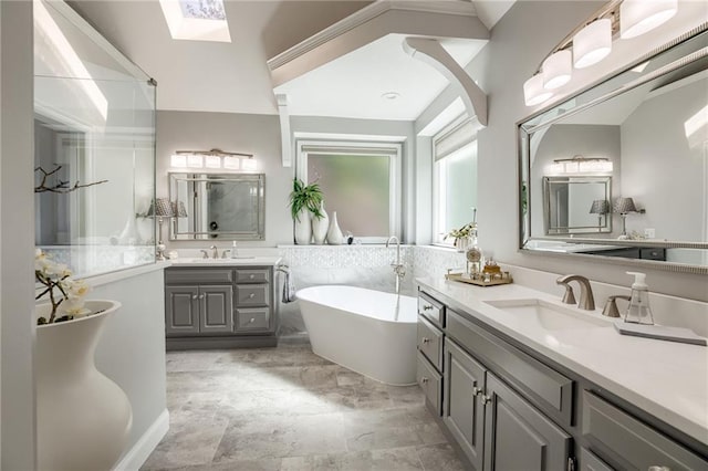 1021 SW Summit Falls Dr, Lees Summit, MO 64081 - bathroom featuring two vanities, a skylight, a freestanding tub, and a shower stall