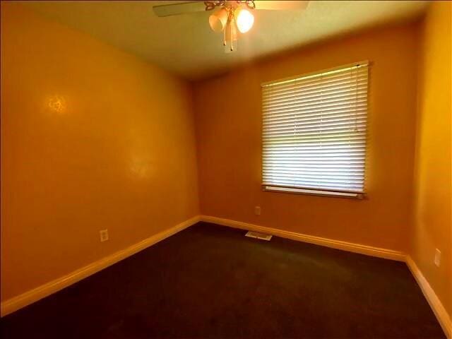 4738 Norton Cir, Kansas City, MO 64128 - spare room featuring ceiling fan and dark colored carpet