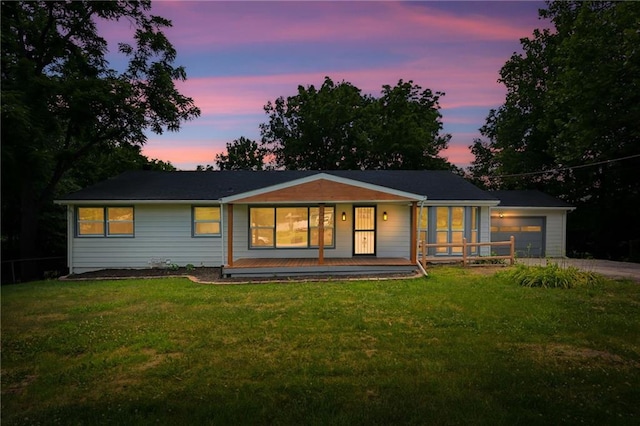 2415 E 126th St, Kansas City, MO 64146 - back of property at dusk featuring a porch, driveway, a garage, and a lawn