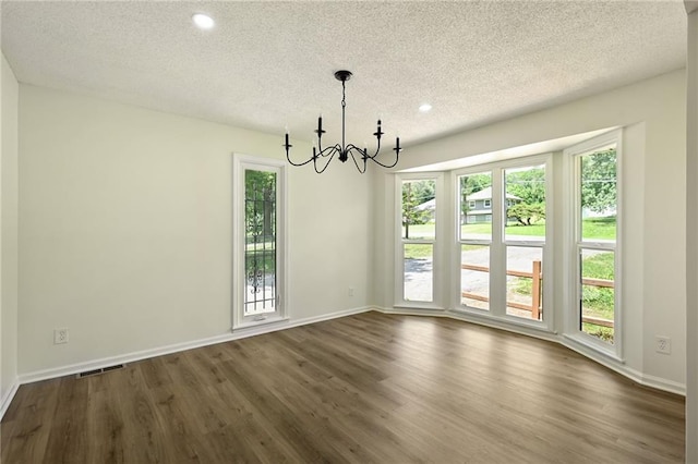 2415 E 126th St, Kansas City, MO 64146 - empty room featuring a textured ceiling, a chandelier, dark wood-type flooring, plenty of natural light, and recessed lighting