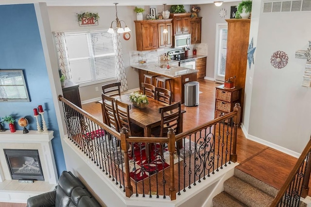 1912 Sequoia Dr, Raymore, MO 64083 - staircase with wood finished floors, a chandelier, and a glass covered fireplace