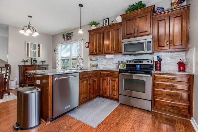 1912 Sequoia Dr, Raymore, MO 64083 - kitchen featuring stainless steel appliances, a peninsula, light wood-type flooring, and backsplash