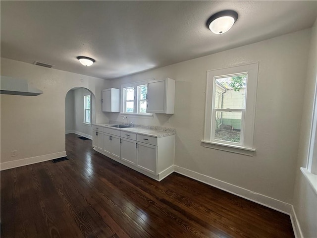2010 N 2nd St, Saint Joseph, MO 64505 - kitchen with arched walkways, dark wood-style floors, light countertops, and white cabinetry