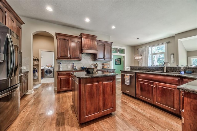 9638 Zarda Dr, Lenexa, KS 66227 - kitchen featuring stainless steel appliances, washer / dryer, a center island, light wood-style flooring, and arched walkways