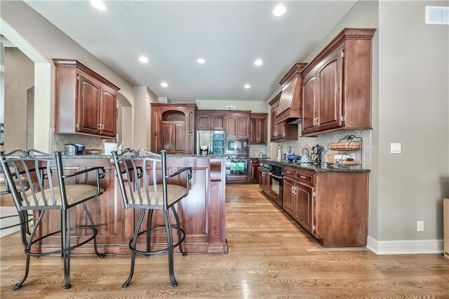 9638 Zarda Dr, Lenexa, KS 66227 - kitchen featuring stainless steel appliances, a peninsula, a kitchen bar, light wood-style flooring, and recessed lighting