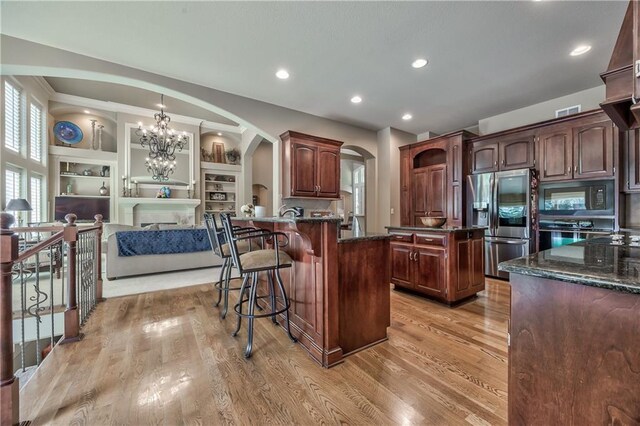 9638 Zarda Dr, Lenexa, KS 66227 - kitchen featuring appliances with stainless steel finishes, arched walkways, a kitchen breakfast bar, a chandelier, and built in features