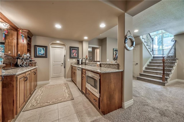 9638 Zarda Dr, Lenexa, KS 66227 - kitchen featuring appliances with stainless steel finishes, arched walkways, light stone counters, brown cabinets, and recessed lighting