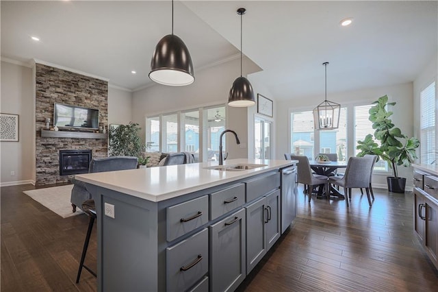 1527 SW Arbor Falls Dr, Lees Summit, MO 64082 - kitchen with gray cabinetry, a stone fireplace, crown molding, light countertops, and healthy amount of natural light