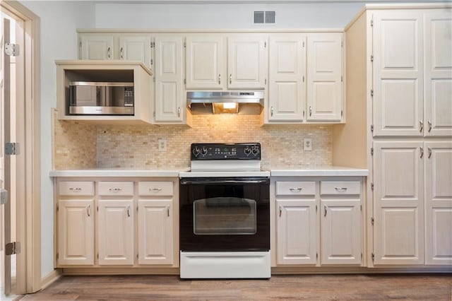 13109 W 65th St, Shawnee, KS 66216 - kitchen featuring white electric stove, stainless steel microwave, under cabinet range hood, light countertops, and tasteful backsplash