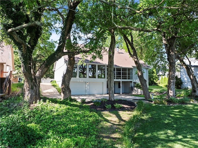 13109 W 65th St, Shawnee, KS 66216 - view of front of property featuring a garage, a sunroom, a front yard, concrete driveway, and stucco siding