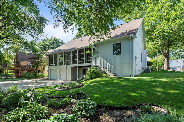 13109 W 65th St, Shawnee, KS 66216 - back of property with a sunroom, concrete driveway, a garage, stairway, and a yard