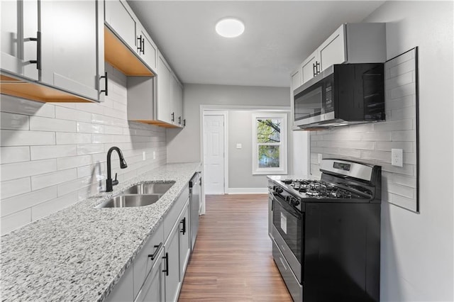 320 N Cedar Ave, Independence, MO 64053 - kitchen featuring appliances with stainless steel finishes, light stone countertops, wood finished floors, and tasteful backsplash