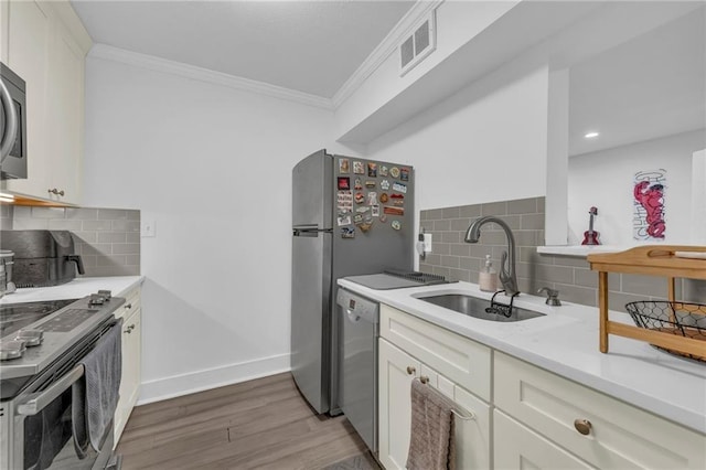 5015 Walnut St Unit A, Kansas City, MO 64112 - kitchen featuring appliances with stainless steel finishes, ornamental molding, tasteful backsplash, light wood-type flooring, and light countertops