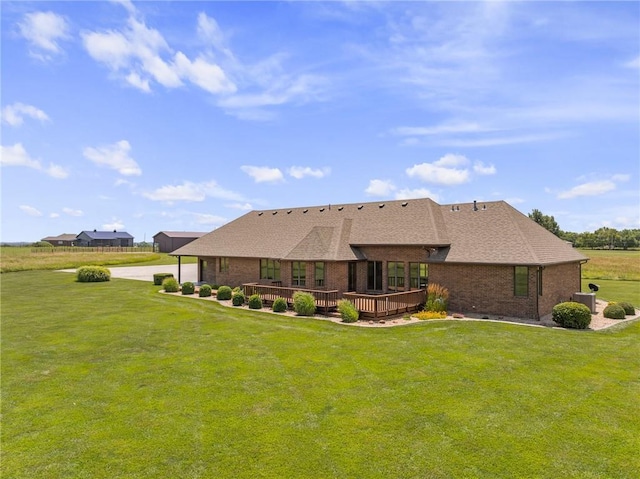 1001 E Park Rd, Garnett, KS 66032 - back of house featuring brick siding, a deck, driveway, a yard, and roof with shingles