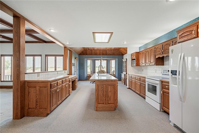 1001 E Park Rd, Garnett, KS 66032 - kitchen featuring white appliances, brown cabinets, light countertops, a kitchen island with sink, and light carpet