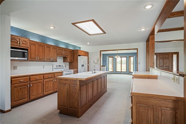 1001 E Park Rd, Garnett, KS 66032 - kitchen with white appliances, light carpet, brown cabinets, a center island with sink, and light countertops