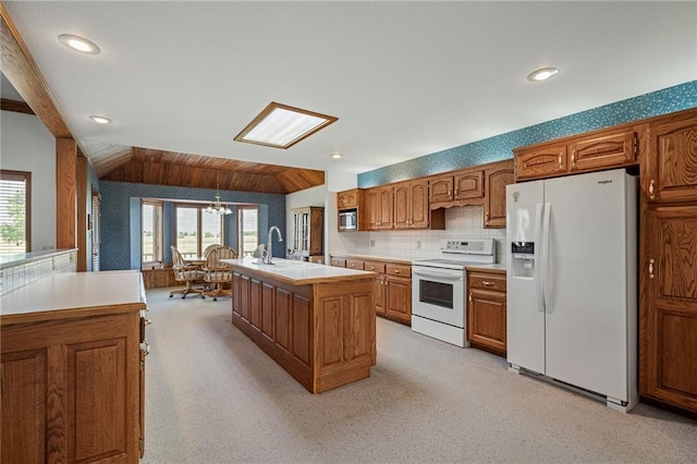 1001 E Park Rd, Garnett, KS 66032 - kitchen with white appliances, light countertops, brown cabinetry, a center island with sink, and light carpet