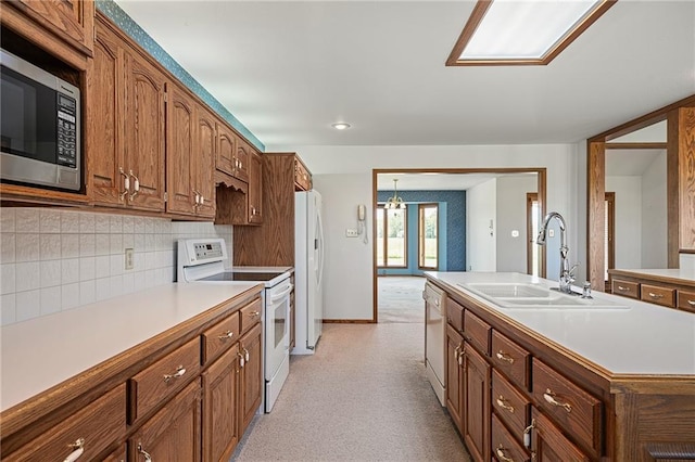 1001 E Park Rd, Garnett, KS 66032 - kitchen with white appliances, light countertops, decorative backsplash, brown cabinets, and a center island with sink
