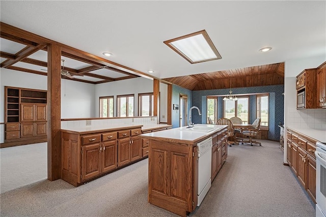 1001 E Park Rd, Garnett, KS 66032 - kitchen with light carpet, white dishwasher, brown cabinetry, an island with sink, and a chandelier