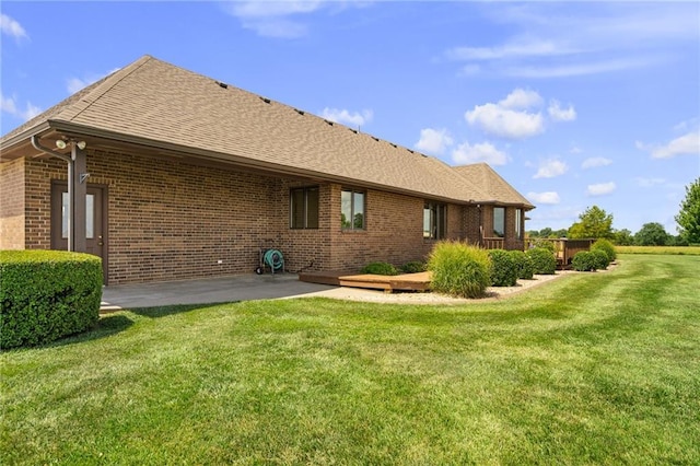 1001 E Park Rd, Garnett, KS 66032 - rear view of property featuring brick siding, a patio area, a yard, and a shingled roof
