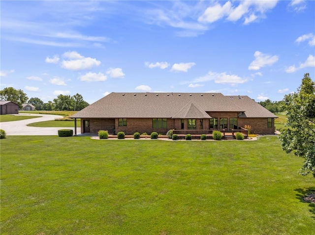 1001 E Park Rd, Garnett, KS 66032 - rear view of house featuring a lawn, brick siding, a deck, and concrete driveway