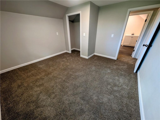 710 E Vine St, Iola, KS 66749 - unfurnished bedroom with dark colored carpet and vaulted ceiling