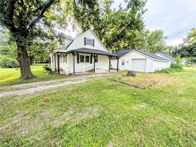 710 E Vine St, Iola, KS 66749 - view of front of property with covered porch, an outbuilding, a front yard, a garage, and driveway