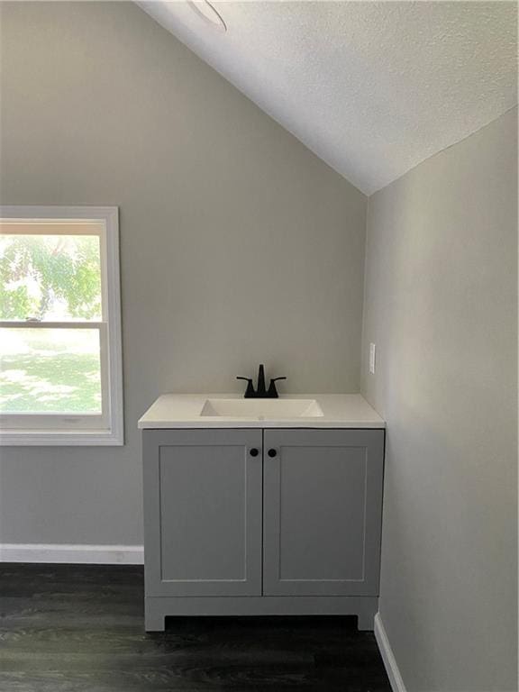 710 E Vine St, Iola, KS 66749 - bathroom with lofted ceiling, wood finished floors, vanity, and a textured ceiling