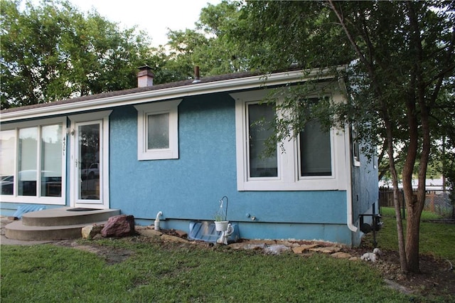 4301 James Ave, Independence, MO 64055 - view of side of property featuring stucco siding and a chimney
