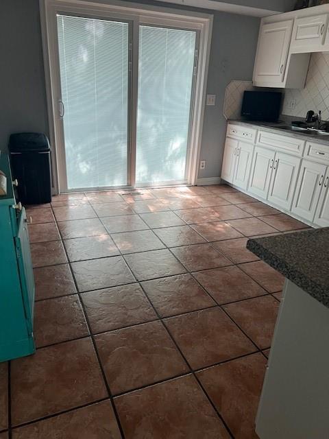 4301 James Ave, Independence, MO 64055 - kitchen featuring tasteful backsplash, white cabinets, dark countertops, and tile patterned floors