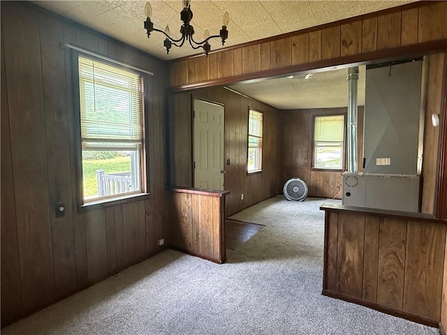 303 Bell St, Richmond, MO 64085 - unfurnished dining area featuring carpet flooring, wooden walls, and a chandelier