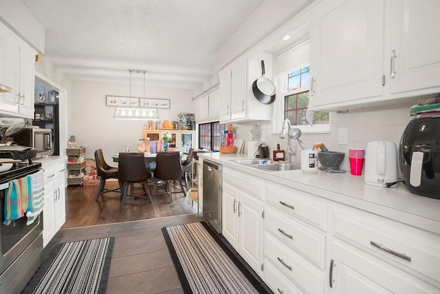 7921 Yecker St, Kansas City, KS 66102 - kitchen featuring appliances with stainless steel finishes, light countertops, white cabinetry, backsplash, and a textured ceiling