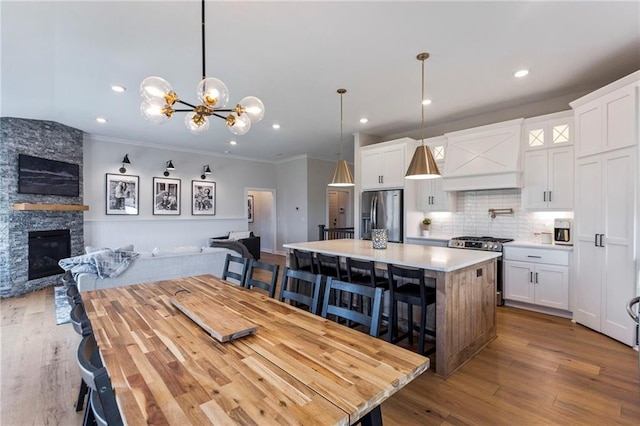 19013 W 188th Ter, Spring Hill, KS 66083 - dining room featuring a chandelier, wood finished floors, ornamental molding, a stone fireplace, and recessed lighting