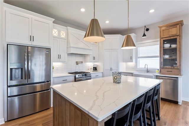 19013 W 188th Ter, Spring Hill, KS 66083 - kitchen with stainless steel appliances, custom range hood, glass insert cabinets, light wood-type flooring, and recessed lighting