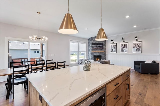 19013 W 188th Ter, Spring Hill, KS 66083 - kitchen with open floor plan, wood finished floors, a stone fireplace, plenty of natural light, and a wainscoted wall