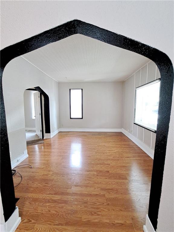 3009 Montgall Ave, Kansas City, MO 64128 - unfurnished room with arched walkways and light wood-style flooring