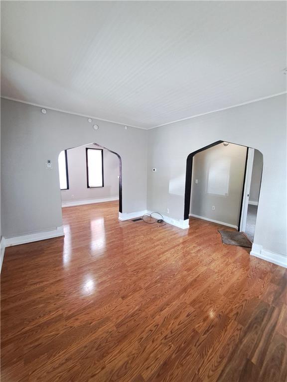 3009 Montgall Ave, Kansas City, MO 64128 - unfurnished living room with arched walkways and light wood finished floors