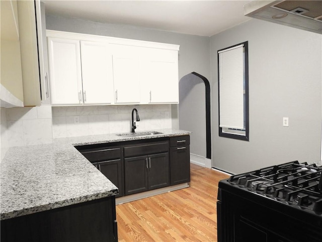3009 Montgall Ave, Kansas City, MO 64128 - kitchen featuring white cabinetry, light wood finished floors, and decorative backsplash