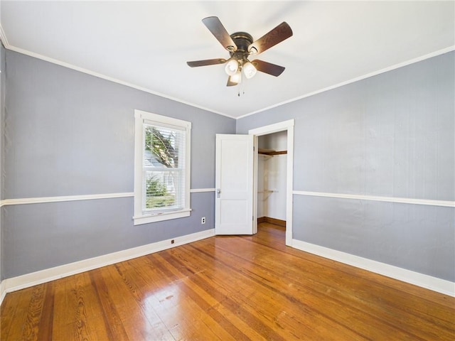 411 S Bismark, Concordia, MO 64020 - unfurnished bedroom featuring wood finished floors, ornamental molding, a ceiling fan, a closet, and a walk in closet
