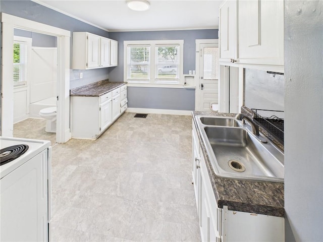411 S Bismark, Concordia, MO 64020 - kitchen featuring white range with electric stovetop, white cabinetry, dark countertops, crown molding, and light flooring