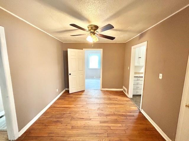 5046 Glenside Ct, Kansas City, MO 64129 - spare room featuring ceiling fan, wood finished floors, a textured ceiling, and crown molding