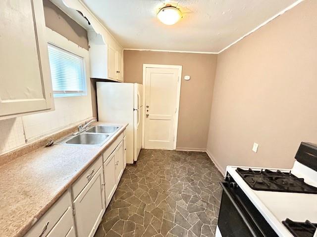 5046 Glenside Ct, Kansas City, MO 64129 - kitchen featuring gas stove, freestanding refrigerator, white cabinets, light countertops, and dark stone finish flooring