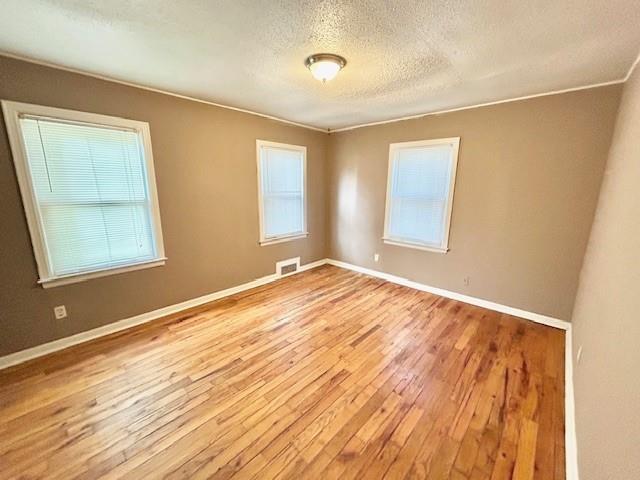 5046 Glenside Ct, Kansas City, MO 64129 - unfurnished room with a textured ceiling and hardwood / wood-style floors